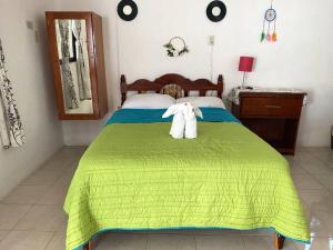 a bedroom with a green bed with a towel on it at Posada Xtakay Bacalar in Bacalar