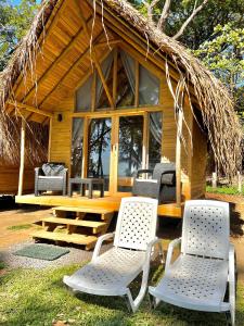 a cabin with chairs and a thatched roof at Hotel Oasis & Surf Camp in Santa Catalina