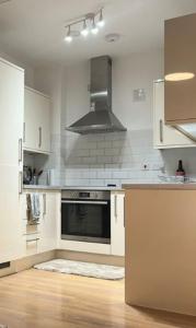 una cucina con armadi bianchi e piano cottura di Modern and Stylish 1bed flat a Barking