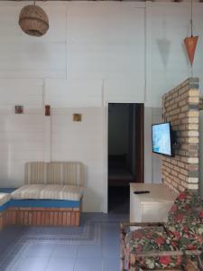 a living room with a couch and a tv at Casa Rústica praia da Ferrugem próximo praia com piscina compartilhada in Garopaba