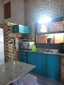 a kitchen with blue cabinets and a counter top at Casa Rústica praia da Ferrugem próximo praia com piscina compartilhada in Garopaba