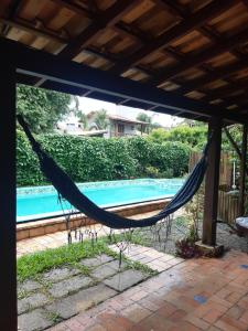 a hammock on a patio next to a pool at Casa Rústica praia da Ferrugem próximo praia com piscina compartilhada in Garopaba