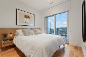 Dormitorio blanco con cama y ventana grande en West Bay Bliss, en Victoria