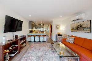 a living room with a orange couch and a flat screen tv at Mariners Court - 4 Laurel St Unit 219 in Rehoboth Beach