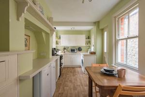 una cucina con pareti verdi e tavolo in legno di Prospect Cottage by Bloom Stays a Hythe