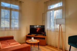 a living room with a flat screen tv and two windows at Casa do Pinheiro, a Home in Madeira in São Vicente