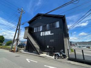 SAMURISE 81INN - Vacation STAY 60981v في Azagawa: مبنى أسود مع سكوتر متوقف على جانب شارع