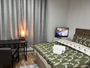 a bedroom with a bed and a desk and a television at JJ Serviced Apartment - Close to Tube Station & Near Central London & Wembley in Northolt