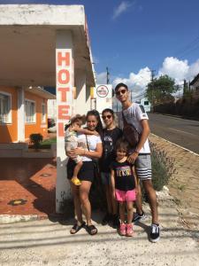 a family posing in front of a gas station at Hotel Pousaria in Guarapuava