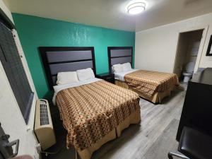 um quarto com duas camas e uma parede verde em Green Garden Inn em Greensboro