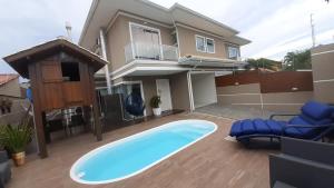 un cortile con piscina e una casa di Casa de Praia em PONTA DAS CANAS, FLORIANÓPOLIS a Florianópolis