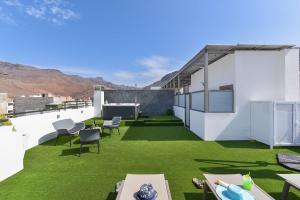 a rooftop patio with green grass and white walls at Apartamento Starlight La Aldea I in San Nicolás