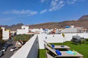 a balcony with tables and chairs and a city at Apartamento Starlight La Aldea I in San Nicolás