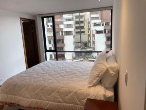 Cama en habitación con ventana grande en Apartamento Quito tenis, en Quito