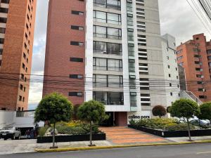 un edificio alto con árboles delante de él en Apartamento Quito tenis, en Quito