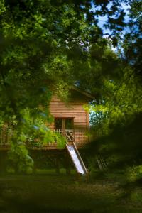 a log cabin with a slide in front of it at Le Monde de Charlie - Les Cabanes in Bellerive-sur-Allier