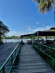 a wooden boardwalk leading to a dock with a boat at Flat no Resort Gran Lençóis in Barreirinhas