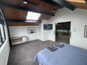 ein Schlafzimmer mit einem großen Bett und einem TV in der Unterkunft The clubhouse in Hamilton
