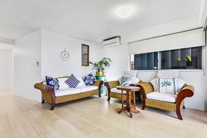 a living room with two couches and a table at Luxury Beach Front Apartment in Urangan