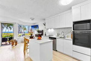 a kitchen with white cabinets and a table with an island at Luxury Beach Front Apartment in Urangan