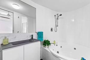 a white bathroom with a tub and a sink at Luxury Beach Front Apartment in Urangan