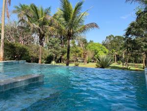 una gran piscina con palmeras en el fondo en Refúgio do Cerrado, en Anápolis