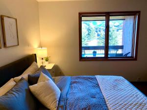 Un dormitorio con una cama azul y una ventana en Beaver Creek/Avon condo on lake with BC ski views, en Avon
