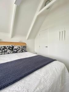 a white bedroom with a bed and a white cabinet at The Loft Matua in Tauranga