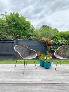 two chairs sitting on a wooden deck with flowers at The Loft Matua in Tauranga