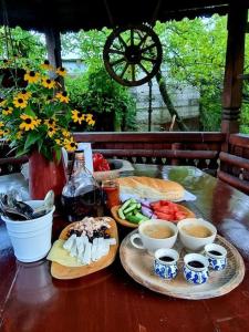 Locuința extraodinară cu șemineu ,grădina , foișor في بريزا: طاولة خشبية مع لوحات من الطعام وأكواب من القهوة