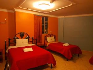 2 camas en una habitación con paredes de color naranja en Hotel Allegria en Quito
