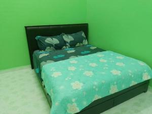 a bed with a blue comforter with flowers on it at PCB PURPLE GUEST HOUSE in Kota Bharu