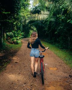 een vrouw die op een fiets over een onverharde weg loopt bij Jaguar Creek in Good Living Camp