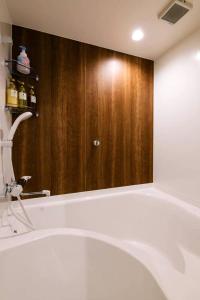 ein Badezimmer mit einer Badewanne und einem großen Spiegel in der Unterkunft TEN APARTMENT HOTEL in Fukuoka