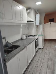 a white kitchen with a sink and a stove at Amplio depto en PB con entrada independiente y doble cochera in Las Heras