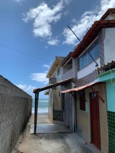 a building on the beach with the ocean in the background at Kitnet Arembepe - Aconchego da Lulu in Arembepe