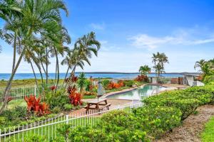 a swimming pool with palm trees and the ocean at Luxury Beach Front Apartment in Urangan