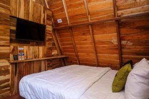 1 dormitorio con 1 cama y TV en una cabaña en Urbanview Villa Kolopaking Kebumen by RedDoorz, en Kebumen