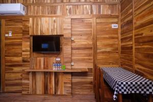 um quarto com paredes de madeira e uma televisão e um banco em Urbanview Villa Kolopaking Kebumen by RedDoorz em Kebumen