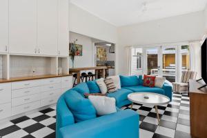 a living room with a blue couch and a kitchen at WARATAH at Queenscliff in Queenscliff