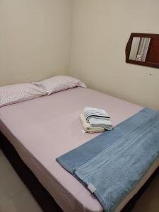 Una cama blanca con dos toallas plegables. en Ap Estacio en Río de Janeiro