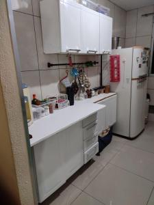 Una cocina con gabinetes blancos y un refrigerador blanco. en Ap Estacio, en Río de Janeiro