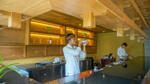 um homem parado numa cozinha a beber de uma caneca em Sakti Garden Resort & Spa em Ubud