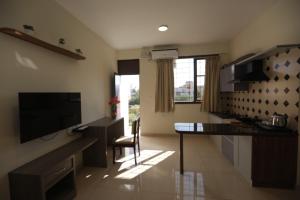 een woonkamer met een keuken met een tafel en een televisie bij Elysian Grand Hotel in Bangalore