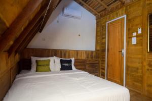 a bedroom with a white bed with wooden walls at Urbanview Villa Lukulo Kebumen by RedDoorz in Kebumen