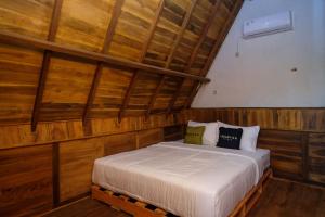 1 dormitorio con 1 cama en una pared de madera en Urbanview Villa Lukulo Kebumen by RedDoorz, en Kebumen