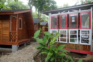 a row of wooden cabins with red and white windows at Urbanview Villa Lukulo Kebumen by RedDoorz in Kebumen