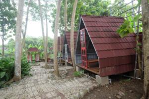 una casa en el bosque con techo rojo en Urbanview Villa Lukulo Kebumen by RedDoorz, en Kebumen