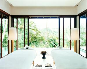 a bedroom with four beds and large windows at COMO Shambhala Estate in Payangan
