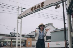 una mujer parada frente a una gasolinera en まちの別邸 緝 shu, en Kochi